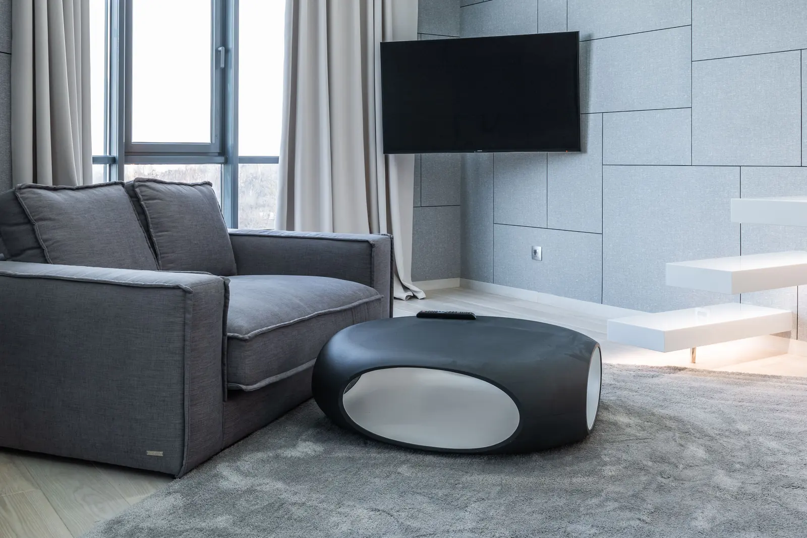 Grey carpeted living room with floor-to-ceiling windows and curtains drawn open